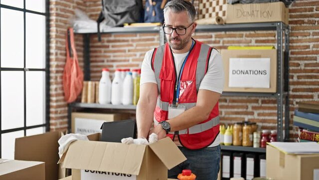Grey-haired man volunteer packing toys to donate at charity center