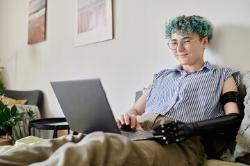 Girl with disability sitting on her bed and using laptop at home