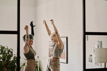 Two lesbian girls doing exercises or dancing together in the room at home