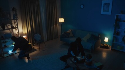 Shot of two burglars going around the apartment, looking for valuables, jewelry. The men are using...