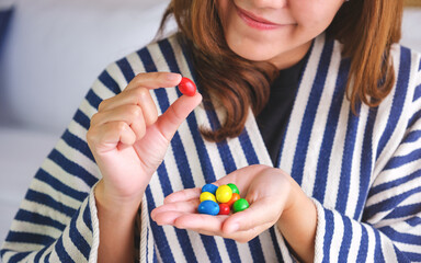 Closeup image of a young woman holding and picking colorful chocolate candy