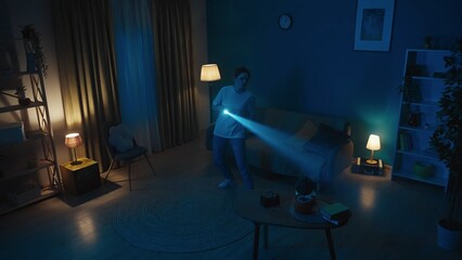 Shot of a young woman going around a dark room in search for burglars, intruders, thieves. She holds a baseball bat and a flashlight.