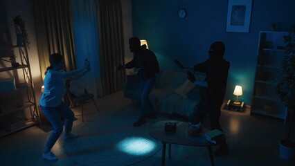 Shot of two burglars going around the apartment, stealing valuables, jewelry, when the owner,...