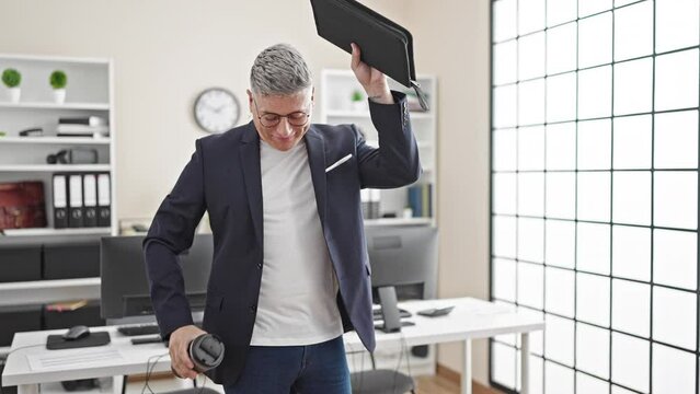 Young caucasian man business worker holding coffee and binder dancing at the office