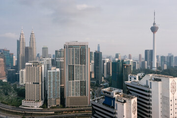 Naklejka premium View of the city and Petronas Twin Towers and Kuala Lumpur Tower on sunny day. Kuala Lumpur, Malaysia.