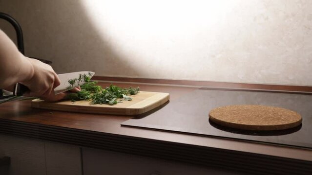 cooking dinner,female hands cut greens with a knife in the kitchen on a cutting board,Healthy lifestyle