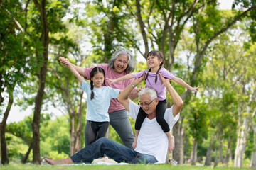 Happy Asian family children having fun and playing with her grandparents in the park - obrazy, fototapety, plakaty
