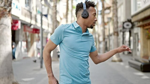African american man listening to music and dancing at street