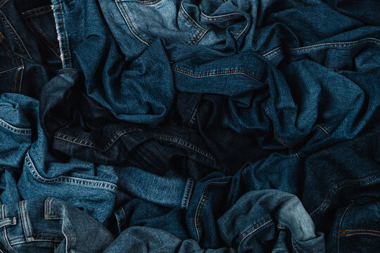 Denim background. Variety of crumpled blue jeans. Top view to stack of jeans denim