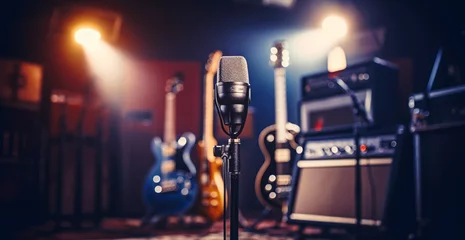 Poster Professional condenser studio microphone over the musician blurred background and audio mixer, Musical instrument Concept.  © Viks_jin