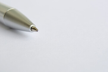 Close-up of metallic pen on white notepad with customizable space for text or ideas.