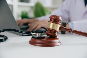 Gavel With Medical Stethoscope while doctor using laptop, Concept of medical law and medical crimes. - obrazy, fototapety, plakaty