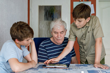 Two Preteen Boys Teaching Grandfather How to Use Internet Safely. Teenage Brothers, School Children...