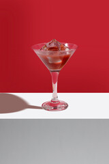 Delicious drink with ice on red background