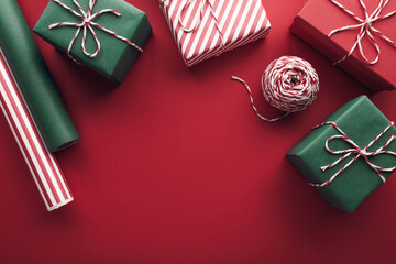 Christmas gift boxes with paper's rools and decorations on red background.