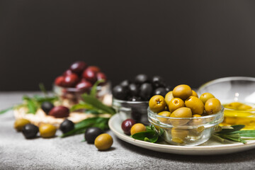 A set of green, red and black olives on a marble background. Various types of olives in bowls and...