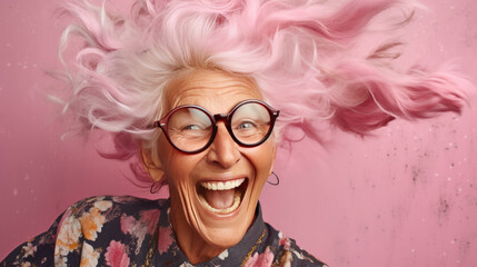 Portrait of a happy senior woman with pink hair and glasses on pink background