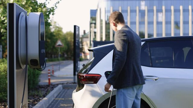Businessman unplugging electric car. Luxury electrical car full. Electrical power filling compete and cable disconnected. Save ecology alternative energy sustainable of future