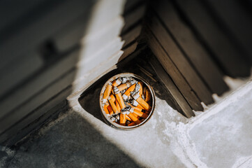 A homemade ashtray from a tin can, an urn with cigarette butts stands in the corner of a brick wall...