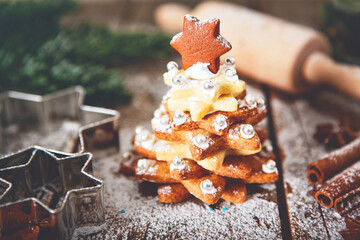 Home made baked Christmas gingerbread tree as a gift for family and friends on wooden background. With colorful lights from Christmas tree on background. With icing sugar gift for xmas