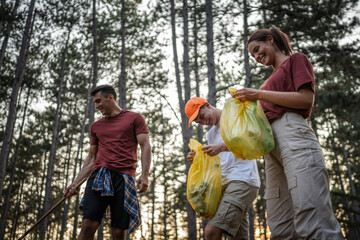 teenage friends young men women pick up waste garbage to clean forest