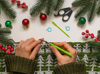 A woman crocheting a festive canvas with Christmas tree pattern.