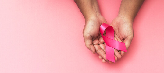 pink ribbon placed on the hand of an obese woman suffering from cancer, world cancer day, healthcare and medicine backdrop, suicide prevention, children health care.