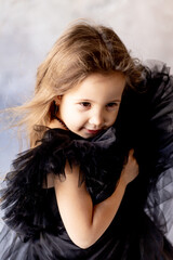 cute smiling little girl in an elegant festive black dress rejoices and smiles,the concept of the holiday