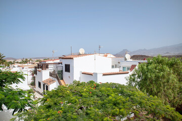 Hot day above the rooftops of a picturesque residence with white villas built in Mediterranean style and surrounded by lush flora in Costa del Silencio, Tenerife, Canary Islands, Spain