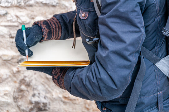 Particolare di ragazza che disegna nel sul quaderno in esterno durante una fredda giornata invernale