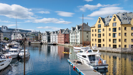 Fototapeta na wymiar Picturesque view of the Brosundet Canal towards docked yachts and fishing boats, famous waterway crossing the old town lined with the beautiful art nouveau buildings, Alesund, Norway