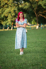Fototapeta premium A young beautiful long-haired girl in a dress is spinning in the park.