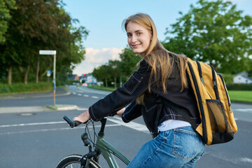 Portrait of teenage student girl with backpack on bicycle