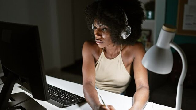 African american woman business worker using computer and headphones taking notes at the office