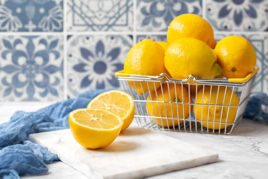 Wire Basket of Fresh Lemons on White Kitchen Counter with Blue Tile Background