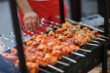Marinated shashlik preparing on a barbecue grill over charcoal. Man cooking marinated shashlik. Shashlik or Shish kebab popular in Eastern Europe.