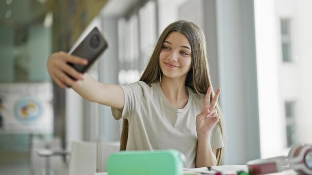 Young beautiful girl student make selfie by smartphone smiling at library