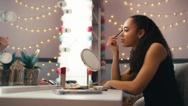 Teenage girl at home in bedroom putting on make up in mirror getting ready for prom or night - shot in slow motion