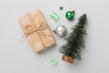 Miniature christmas tree with gift box and decor on color background