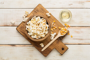 Prepared popcorn with ingredients on wooden background, top view