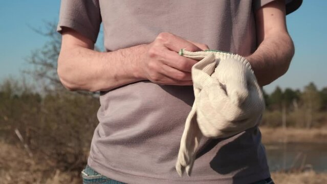 close up man puts protective work gloves on his hands. work uniform, work clothes and accessories, hand protection. slow motion.