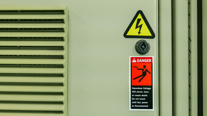 A sign warning of high voltage equipment is posted on the front of the electrical control cabinet. Industrial electrical work concepts and safety