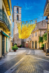 The streets of Beziers, in the Languedoc region of the South of France, are decorated for summer with overhanging decorations made of gold disks, that shine in the sunshine and blow in the wind
