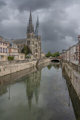 Fototapeta premium Chalons-en-Champagne, France - 09 01 2023: Profile View of the Collegiate Church of Notre-Dame-en-Vaux and reflection on Canal water.