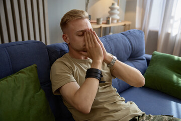 Depressed soldier suffering from military PTSD covering face with hands