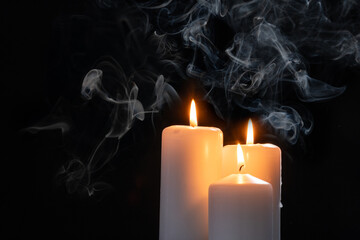 three lit candles on a black background with copy space