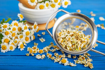 Dry chamomile flowers on a wooden table. Soothing chamomile tea. Herbal drink. flat layout. Space for text.Copy space.Medical prevention and immune concept. Folk alternative medicine.