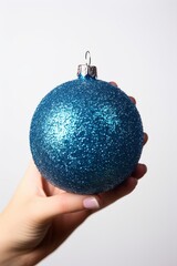 Photo of a hand holding a blue and silver Christmas Bauble against a clean white backdrop created with Generative AI technology