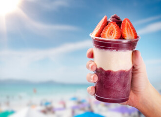 A bowl of açaí topped with strawberries on the beach.Acai bowl on tropical beach