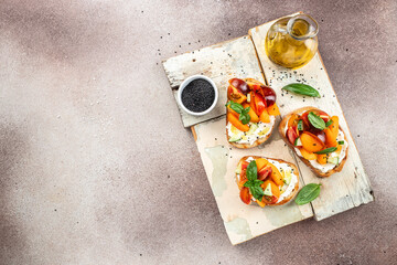Toast, snack, bruschetta, sandwich with cream cheese, peaches, tomatoes and green basil leaves, Concept healthy and balanced eating. place for text, top view